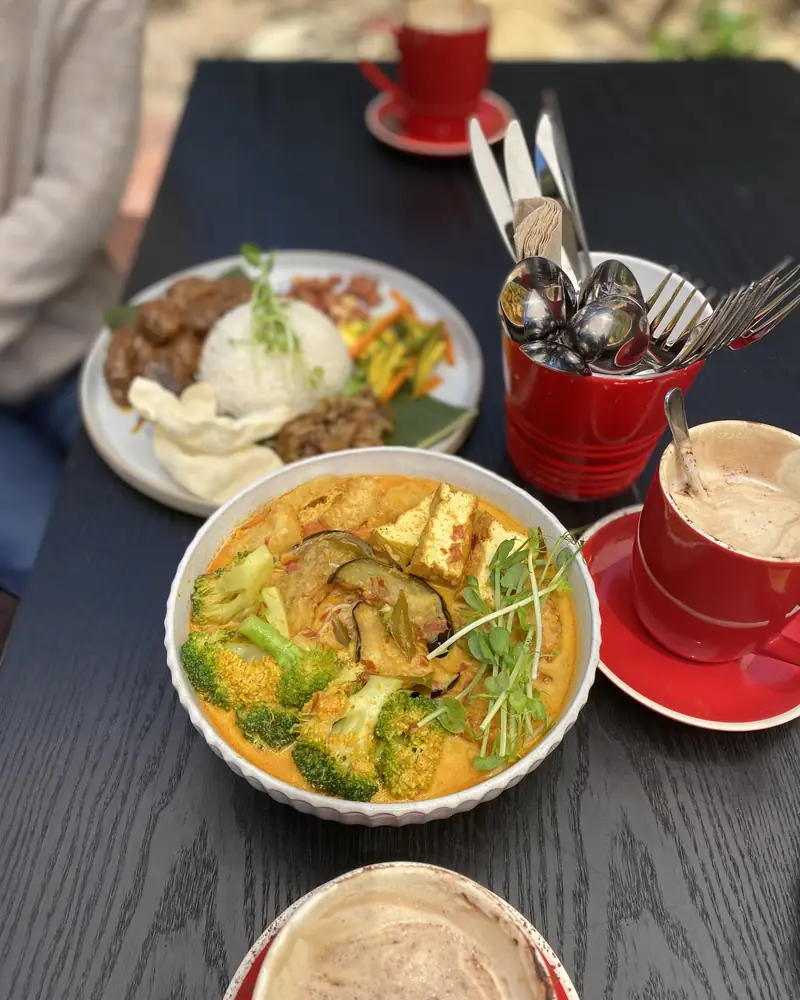 Laksa, rice and coffee in red cups on a courtyard table
