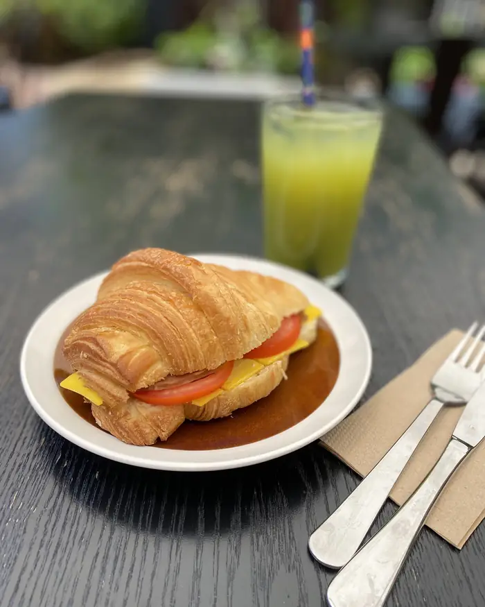 Croissant with a fresh green juice on a courtyard table