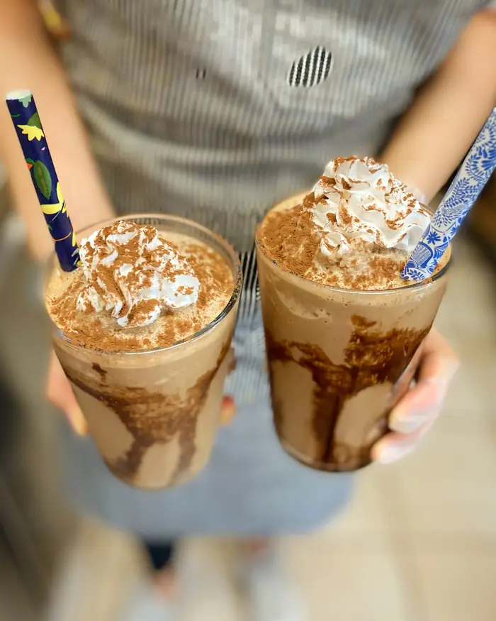 Two iced frappes with chocolate sauce and whipped cream